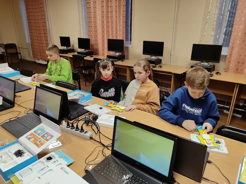 Четверо учнів за столами з ноутбуками складають електронні схеми на STEM-занятті