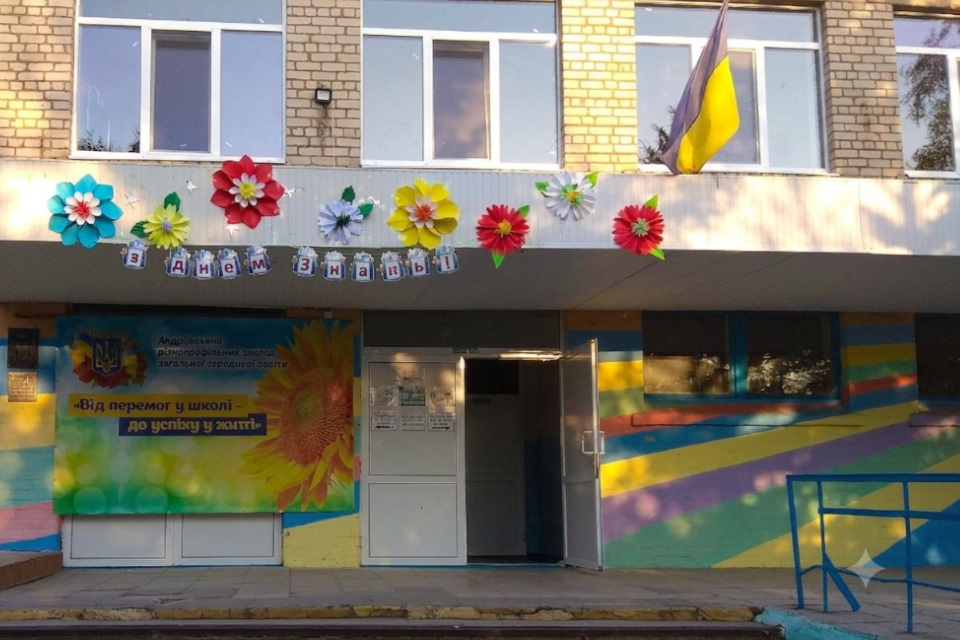 Головний корпус Андріївської гімназії: двоповерхова будівля з розмальованим у кольори веселки ґанком і державним прапором